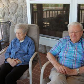 A serene moment shared by an elderly couple on their porch.