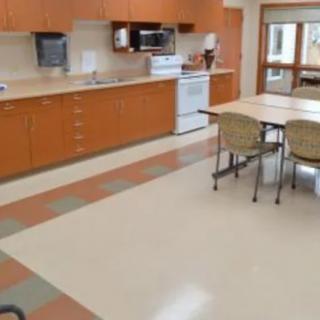 A spacious kitchen with wooden cabinets, a table and chairs, and various appliances.