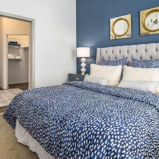 A stylish bedroom with a blue accent wall, featuring a bed with patterned bedding and a view into a walk-in closet.