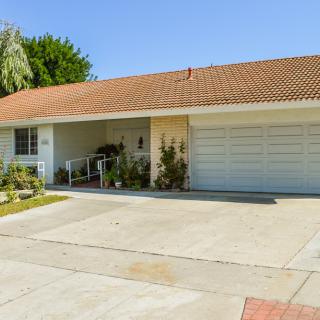 A suburban house with a two-car garage and a driveway under a clear blue sky.