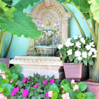 A serene garden fountain surrounded by vibrant flowers and lush greenery.