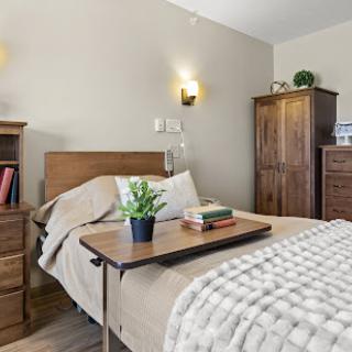 A cozy bedroom featuring wooden furniture, a neatly made bed, and decorative elements for a warm atmosphere.