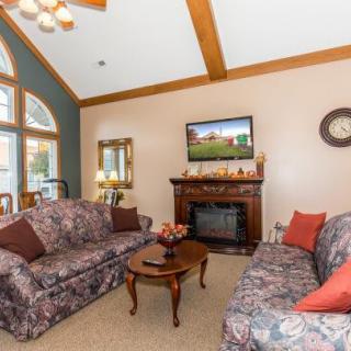 A cozy living room featuring a fireplace and floral patterned sofas with a mounted television above the mantel.