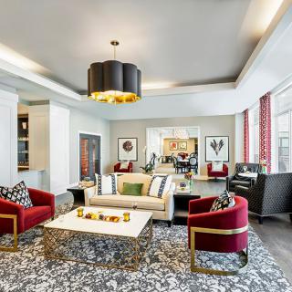 A stylish living room with modern furniture and luxurious decor, featuring a chandelier and artwork on the walls.