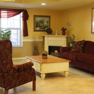 A cozy living room with a sofa, armchair, and fireplace.