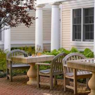 A cozy outdoor patio with tables and chairs surrounded by greenery.