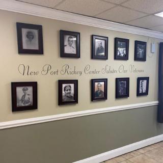 A hallway features a collection of framed black and white photos arranged in two rows, accompanied by elegant script text on the wall.