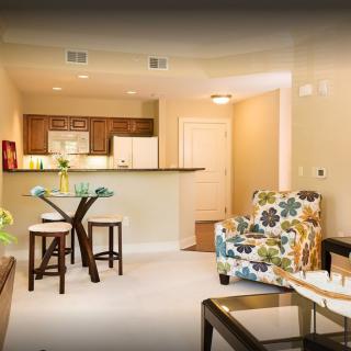 A cozy living room with a view of the kitchen, featuring modern furniture and colorful decor.