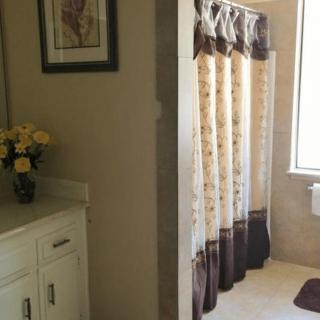 A cozy bathroom with a floral shower curtain and decorative elements.