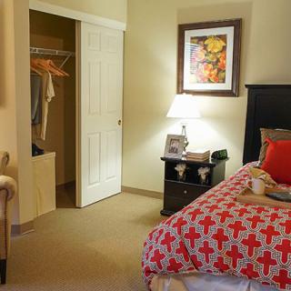 A cozy bedroom with a neatly made bed and an open closet.