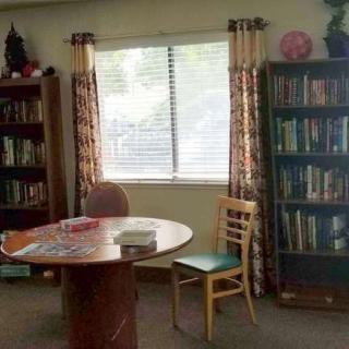 A cozy library corner with a table, chairs, and bookshelves by the window.