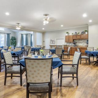 An inviting dining area with neatly set tables, surrounded by a cozy kitchen space.