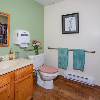 A well-organized bathroom with a toilet, sink, and neatly arranged towels.