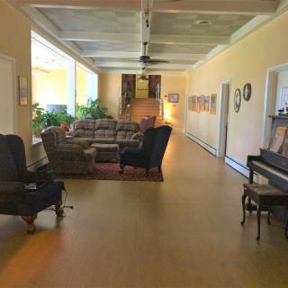 A spacious living room with seating area, piano, and decorative plants.