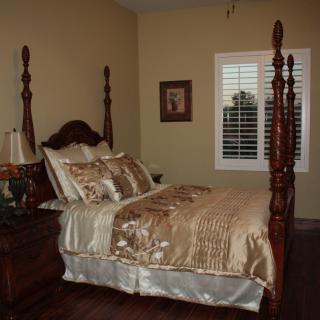 A cozy bedroom with a traditional four-poster bed, complemented by elegant beige and gold bedding.