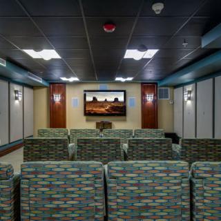 A small movie theater with patterned seating and a large screen.