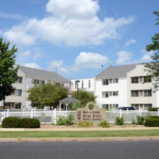 A view of a residential building with neatly landscaped grounds under a partly cloudy sky.