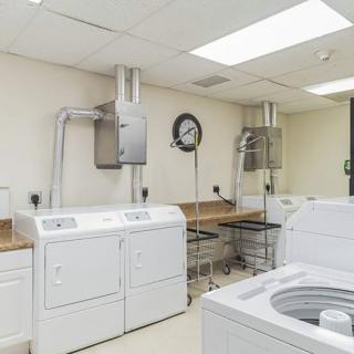 A clean and organized laundry room featuring multiple washing machines and dryers.