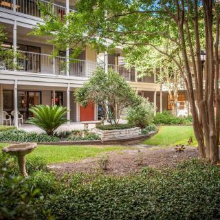 A serene courtyard surrounded by greenery and a multi-level building.