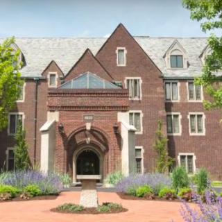 A historic brick building on a college campus with a landscaped entryway.