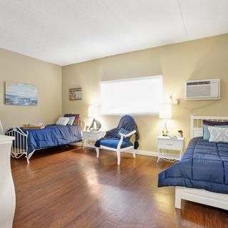 A cozy bedroom with two twin beds, blue bedding, and wooden floors.