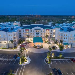Aerial view of a well-lit hotel building with surrounding parking area at night.