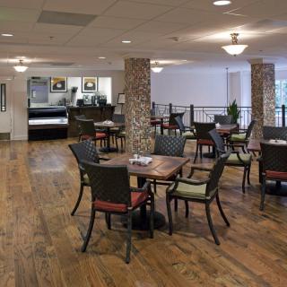 A spacious dining area with multiple tables and chairs on a wooden floor.