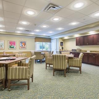 A well-lit conference room featuring multiple tables and striped chairs, decorated with artwork on the walls.