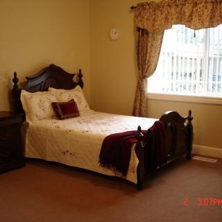 A cozy bedroom with a wooden bed and elegant curtains by the window.