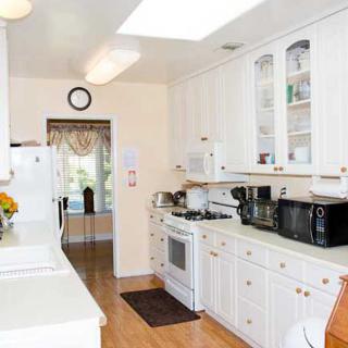 A bright, modern kitchen with white cabinets and a wooden floor.