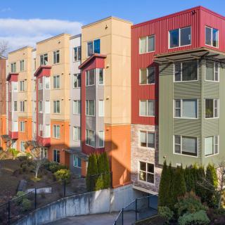 A colorful apartment building with multiple stories, featuring various shades of green, red, and beige in an urban setting.