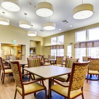 A modern dining room with elegant chairs and tables, featuring ample natural light from large windows.