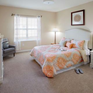 A cozy bedroom with a neatly made bed, soft lighting, and tasteful decor.