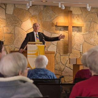 A pastor delivers a sermon to a congregation in a church setting.