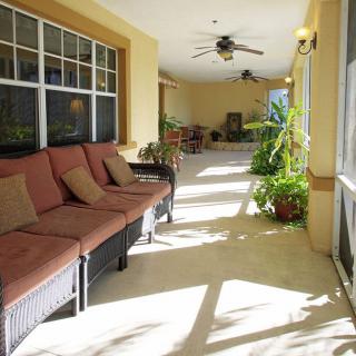 A sunlit porch with comfortable seating and plants, creating a relaxing atmosphere.