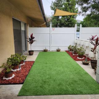 A well-designed outdoor space featuring lush artificial grass and decorative flower pots.