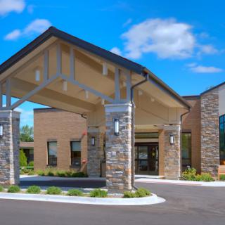 A modern building featuring a welcoming entrance with stone accents and a clear blue sky.