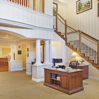 A welcoming office lobby with a wooden reception desk and elegant staircase.