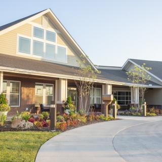 A suburban house with a well-maintained garden and driveway on a sunny day.