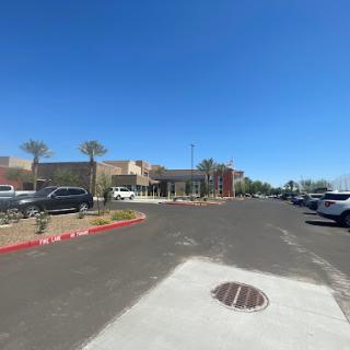 A sunny day at a commercial parking lot with palm trees and various parked cars.