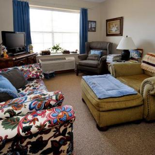 A cozy living room with various furniture, including a sofa, armchair, and a television.