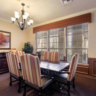 A cozy dining room with a large table, upholstered chairs, and a chandelier.