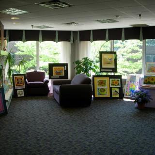 A cozy art gallery with armchairs, surrounded by paintings and greenery.