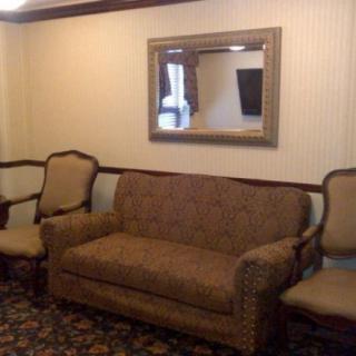 A cozy living room setup featuring a sofa, two armchairs, and a large mirror.