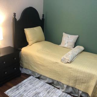 A cozy bedroom with a single bed, nightstand, and warm lighting.