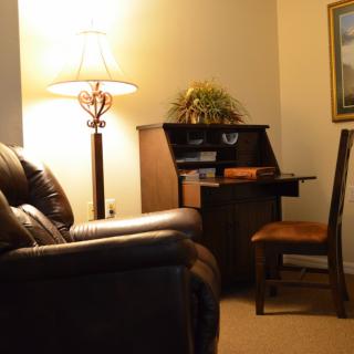 Cozy living room with a sofa, lamp, and small desk area.