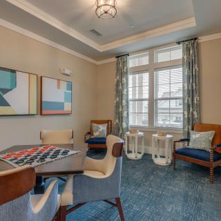 A cozy living room with a table and chairs, modern artwork, and large windows.