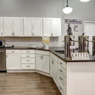 A modern kitchen with white cabinets and a dedicated coffee station on the countertop.
