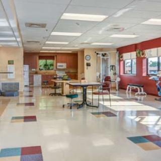 A spacious and well-lit waiting area featuring tables and chairs in a modern design.