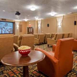 A cozy home theater with comfortable seating and a projector screen, featuring a bowl of popcorn on a side table.
